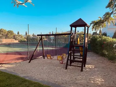 a playground with a swing set on a tennis court at Vila Rafaella - Praia de São Rafael in Sesmarias