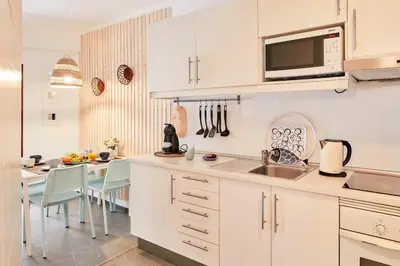 a kitchen with white cabinets and a sink and a table at Casas Barulho Apartment Old Town in Albufeira