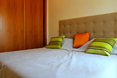 a bed with green and orange pillows on it at Vilamoura Typical 3 With Pool by Homing in Quarteira