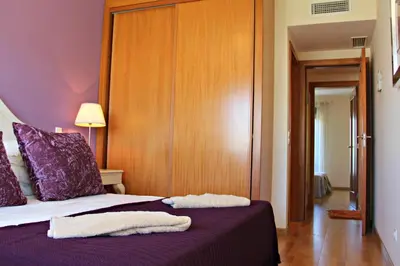 a bedroom with a purple bed with two towels on it at Vilamoura Typical 3 With Pool by Homing in Quarteira