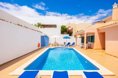 a swimming pool in a villa with blue chairs at Villa Santa Maria in Albufeira