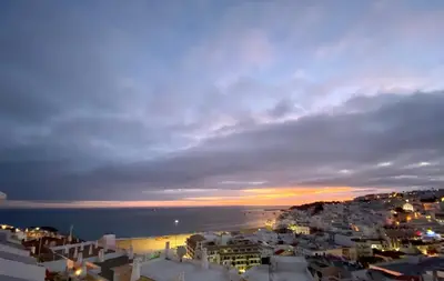 a view of a city at night with the ocean at Fantastic view over the sea in Albufeira