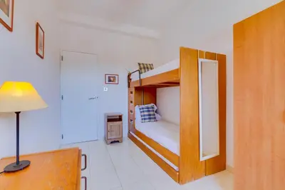 a bedroom with a bunk bed and a desk with a lamp at Apartamento Farol com piscina e estacionamento in Vilamoura
