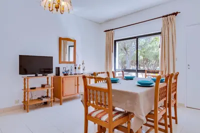 a dining room with a table and a tv at Apartamento Farol com piscina e estacionamento in Vilamoura