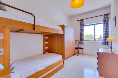 a bedroom with two bunk beds and a desk at Apartamento Farol com piscina e estacionamento in Vilamoura