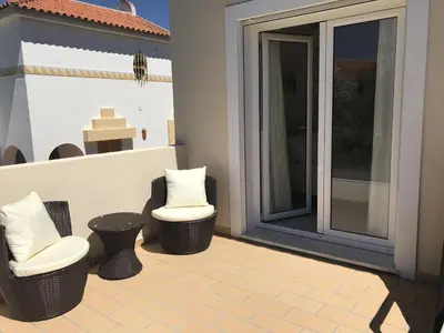 a patio with two chairs and two stools on a porch at 4 Bedroom Villa with Heated Pool close to Old Village in Vilamoura