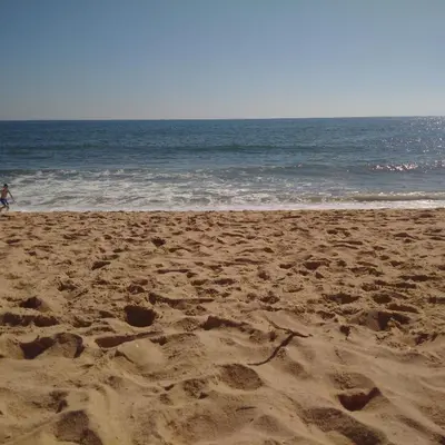 a person walking on a sandy beach near the ocean at 4 Bedroom Villa with Heated Pool close to Old Village in Vilamoura