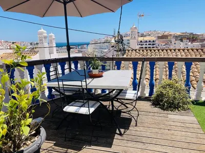 a table and chairs on a balcony with an umbrella at Villa 2BDR with sea view, private pool in Albufeira
