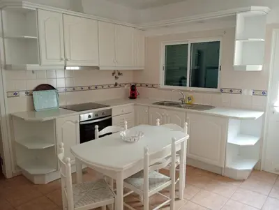 a kitchen with white cabinets and a table and chairs at Albufeira INN - Mulatinho V3 in Olhos de Água