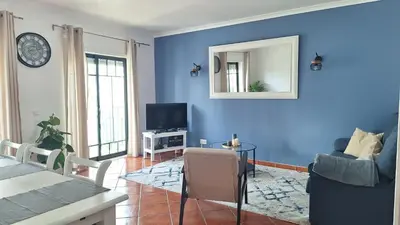 a living room with blue walls and a table and a tv at Apartamento Olhos do Mar in Olhos de Água