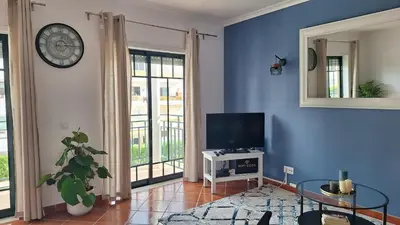 a living room with a tv and a clock on the wall at Apartamento Olhos do Mar in Olhos de Água