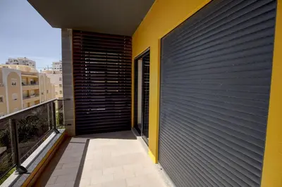 a balcony with a black and yellow wall at Parque Atlântico Modern Seaview Apartment with Pool and Tennis Court in Cavacos