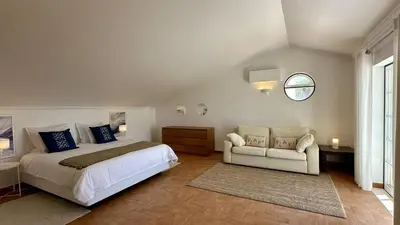 a bedroom with a bed and a couch and a window at Pine Cliffs by Check-in Portugal in Albufeira
