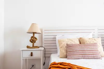 a white bedroom with a bed with a lamp on a night stand at Urban Bliss Guesthouse I in Faro