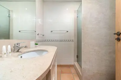 a bathroom with a sink and a shower at Stylish 2BR Ground Floor Apartment in Vila Sol, Direct Garden and Poolside Acces in Quarteira