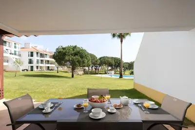 a table with a bowl of fruit on a patio at Stylish 2BR Ground Floor Apartment in Vila Sol, Direct Garden and Poolside Acces in Quarteira