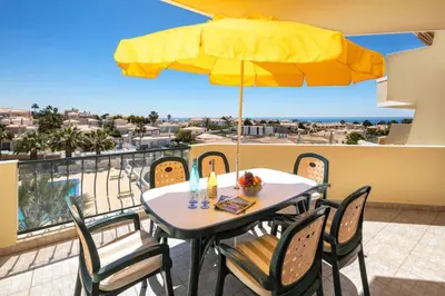 a table and chairs with a yellow umbrella on a balcony at Lovely 2-Bed Apartment in Sao Rafael in Albufeira