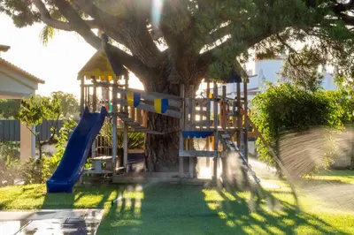a playground with a slide in front of a tree at Ma Vie La in Vale de Carros