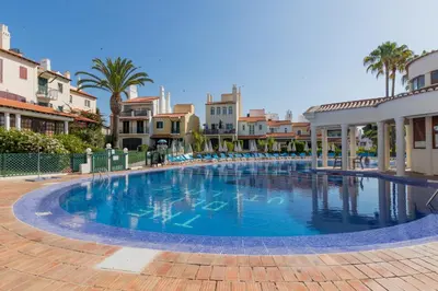 a large swimming pool with palm trees and buildings at Old Village- 2A Village Street in Quarteira
