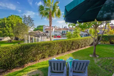 two chairs and an umbrella sitting on the grass at Old Village- 1A Village Gate in Quarteira