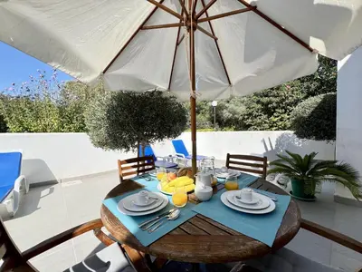 a wooden table with an umbrella and some food on it at Vilamoura Club Villa 1 With Pool by Homing in Vilamoura