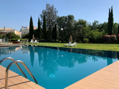a swimming pool with two lawn chairs and trees at Vilamoura Club Villa 1 With Pool by Homing in Vilamoura