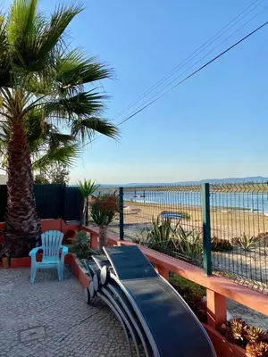 a beach with people sitting on the sand and water at Casa da Ria in Faro
