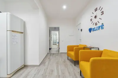 a waiting room with yellow chairs and a clock on the wall at Blife Antonya private rooms at 3rd floor in Faro