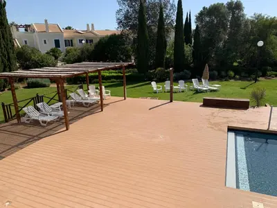 a wooden deck with chairs and a swimming pool at Vilamoura Club Villa 3 With Pool by Homing in Vilamoura