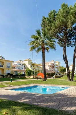 a swimming pool with a palm tree and some buildings at #243 Jardins de Santa Eulália H23 by Home Holidays in Albufeira