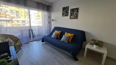 a living room with a blue couch and a window at Apartamento T1 centro Albufeira in Albufeira