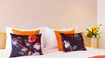a bed with two pillows and a vase with flowers at Arts by Loulé - Alojamento de Charme in Loulé