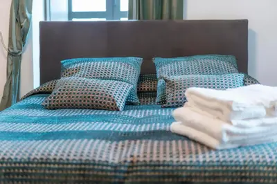 a blue bed with pillows and a pile of towels at Oakmoon House in Faro