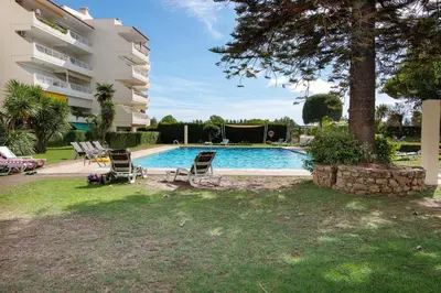 a swimming pool with two chairs and a building at T1 em Vilamoura - Parque Mourabel in Vilamoura
