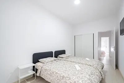 a white bedroom with a bed and a mirror at GrowIN Stay Mercado in Faro