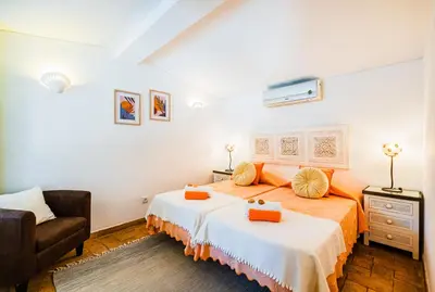 a bedroom with two beds and a chair in it at Villa Alice by Algarve Vacation in Albufeira