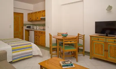 a living room with a kitchen and a table with a television at Ourabay Hotel Apartamento - Art & Holidays in Albufeira