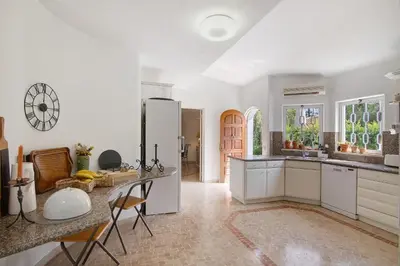 a kitchen with white cabinets and a table and chairs at Casa Isabella in Vilamoura