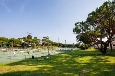 a group of people playing tennis on a tennis court at Villa Carlos in Loulé