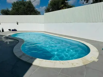 a large blue swimming pool next to a white wall at Casa Da Amélia in Albufeira