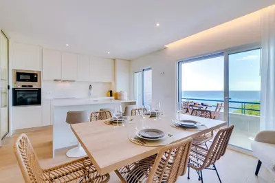 a kitchen and dining room with a table and chairs at Apartamento Gaivota frente-mar in Quarteira