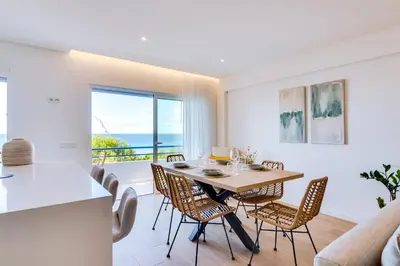 a kitchen and dining room with a table and chairs at Apartamento Gaivota frente-mar in Quarteira
