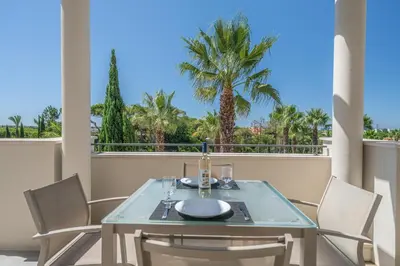 a table and chairs on a balcony with palm trees at Vilamoura Pine Hills with Pool by Homing in Vilamoura