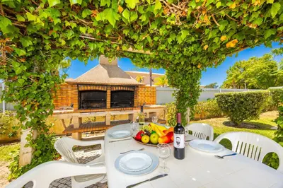 a table with a bowl of fruit and a bottle of wine at Villa Coute Real in Quarteira
