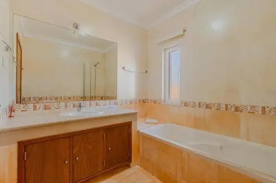a bathroom with a tub and a sink and a mirror at Villa Coute Real in Quarteira