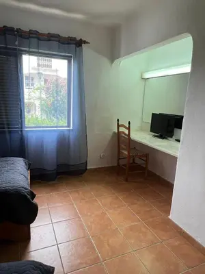 a room with a window and a desk with a television at Apartamento São Rafael Holidays in Albufeira