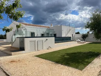 a white house with glass doors and a yard at Monte Gerações - Complete House - Heated pool - Typical Algarvian - close to Quinta Lago Vale Lobo and Vilamoura in Almancil