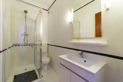 a bathroom with a glass shower and a sink at Garnero Apartment by HelloVacations in Albufeira
