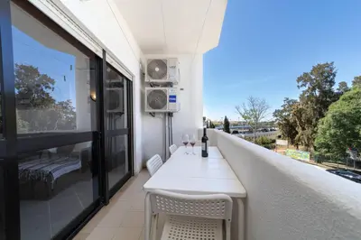 a white table and chairs on a balcony with a view at Garnero Apartment by HelloVacations in Albufeira