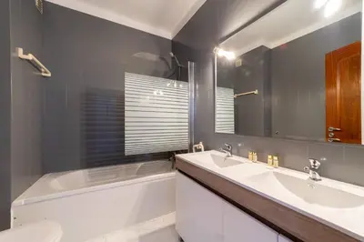 a bathroom with two sinks and a tub and a toilet at Garnero Apartment by HelloVacations in Albufeira